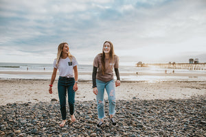 Two females laughing and walking on the beach wearing reef-safe NÖZ sunscreen.